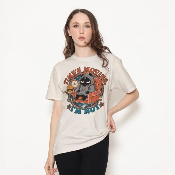 black-scowl-times-moving-beige-tshirt-model Female model wearing a funny lazy beige t-shirt with the 'Time's Moving. I'm Not.' graphic.