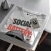 blackscowl-unisex-tee-social-battery-low-folded-tag-detail Folded Black Scowl tee with "Social Battery Critically Low" design and custom tag