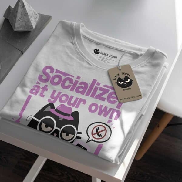 socialize-at-your-own-risk-tshirt-white-mockup-tag Detailed mockup of the White t-shirt, folded, highlighting the anti-social design and the Black Scowl tag.