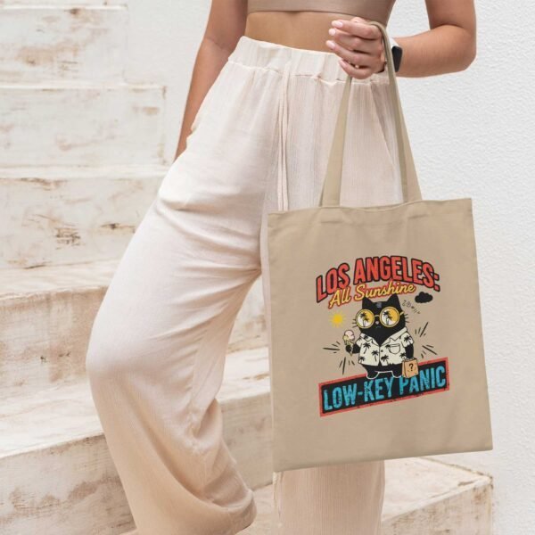 woman-with-low-key-panic-tote-la-setting Woman with the Oyster-colored Black Scowl tote bag, ideal for daily errands and existential dread in the city.