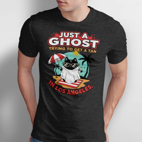 Black Scowl graphic t-shirt featuring a black cat wearing a ghost sheet and sunglasses on a beach. Text reads Just A Ghost Trying To Get A Tan In Los Angeles.