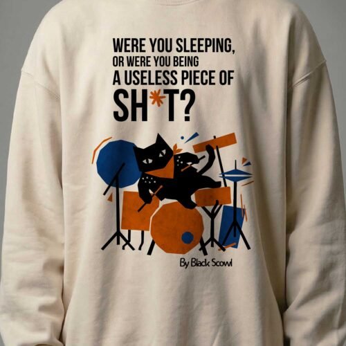 Close-up detail of the Black Scowl cynical cat playing drums and offensive dark humor text Were you sleeping or being a useless piece of sh*t on premium fleece.