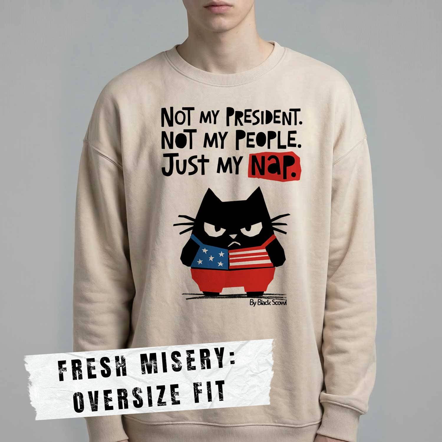 Male model wearing Black Scowl heavyweight oversize sweatshirt with a sarcastic political quote Not My President and a cynical cat graphic.