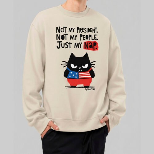 Front lifestyle view of a model wearing the Black Scowl sand-colored crewneck sweatshirt. The urban streetwear design features a sarcastic grumpy cat wearing a USA flag and the edgy quote "Not my President. Not my People. Just my nap."
