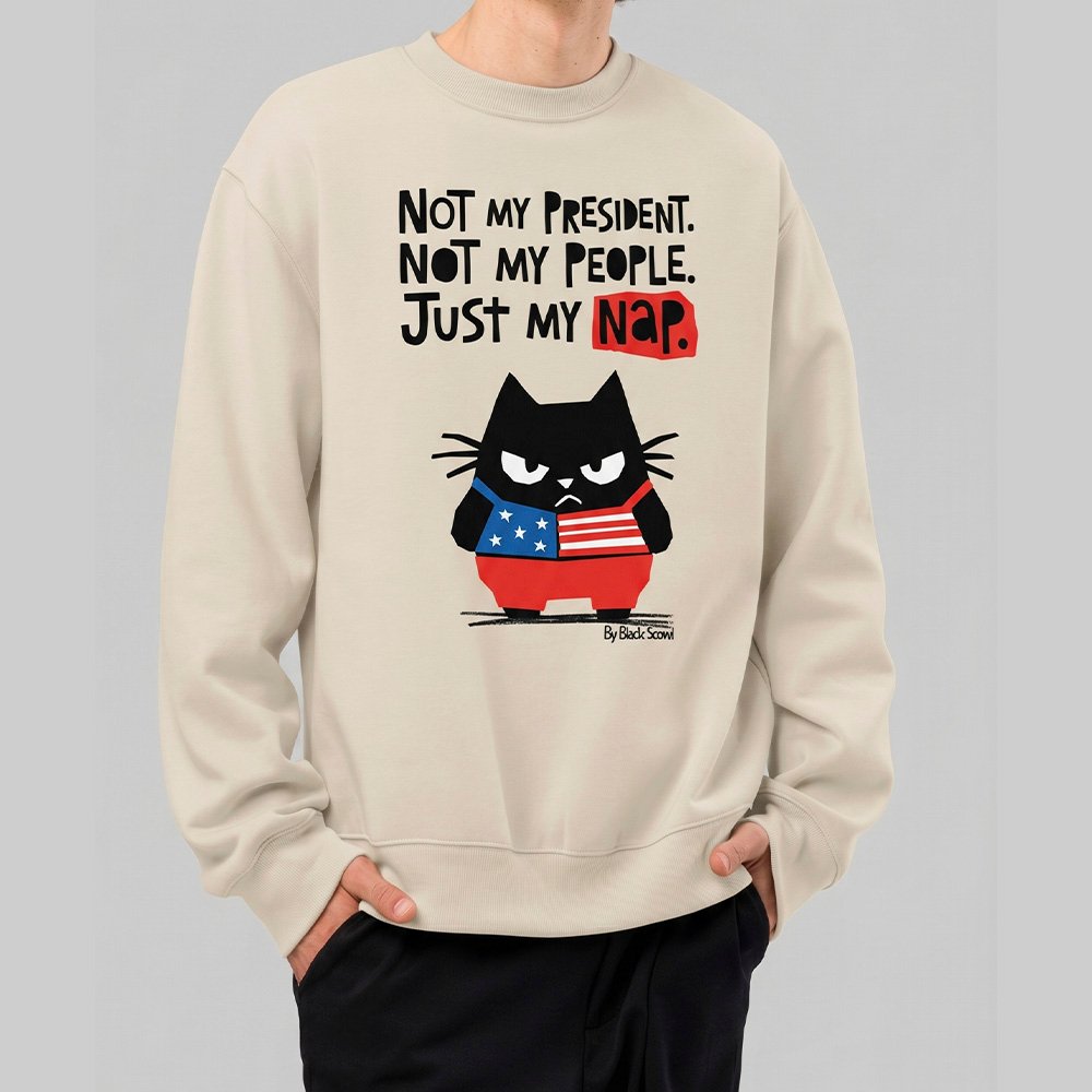 Male model wearing Black Scowl heavyweight oversize sweatshirt with a sarcastic political quote Not My President and a cynical cat graphic.