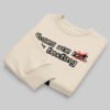 Folded flat lay of the Black Scowl sarcastic crewneck sweater in beige, displaying the premium print of the edgy "texting his ex" urban fashion graphic.