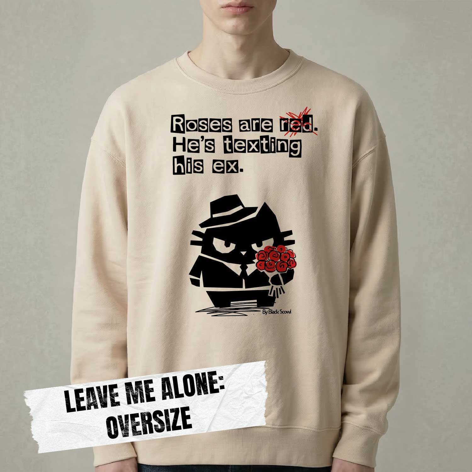 Male model wearing Black Scowl heavyweight oversize sweatshirt with a sarcastic quote about a toxic ex and a cynical cat holding red roses.