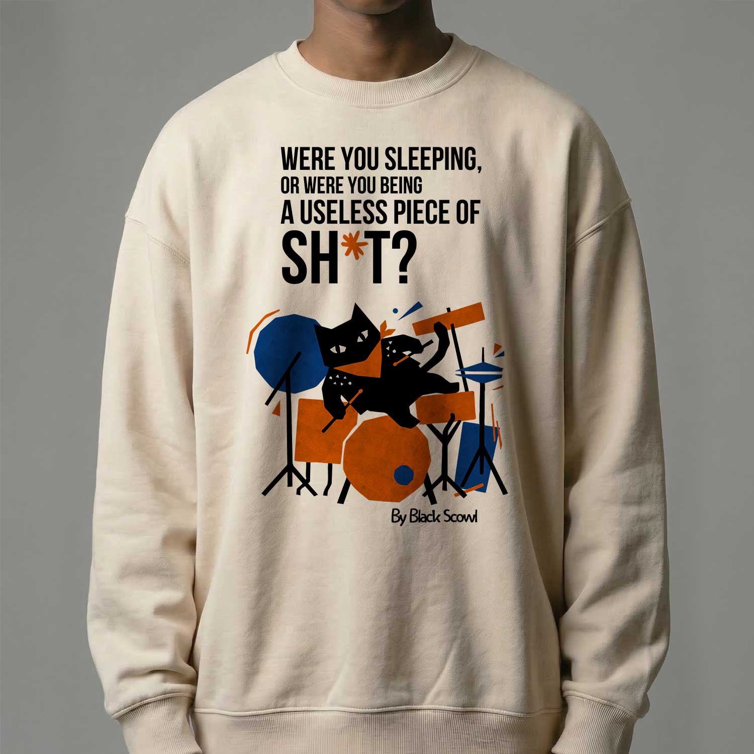 Male model wearing Black Scowl heavyweight oversize sweatshirt with a sarcastic dark humor quote about being useless and a cynical drummer cat graphic.
