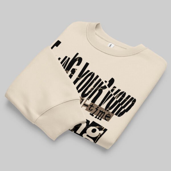 Folded Black Scowl beige sweatshirt displaying the avant-garde style graphic print, isolated on a light background.