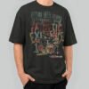 Front view of a male model wearing a Black Scowl black heavyweight t-shirt featuring a cynical drummer cat graphic with "Hitting These Drums To Drown Out Your Pathetic Existence" text.