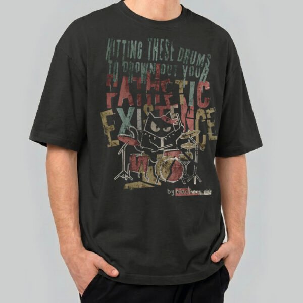 Front view of a male model wearing a Black Scowl black heavyweight t-shirt featuring a cynical drummer cat graphic with "Hitting These Drums To Drown Out Your Pathetic Existence" text.