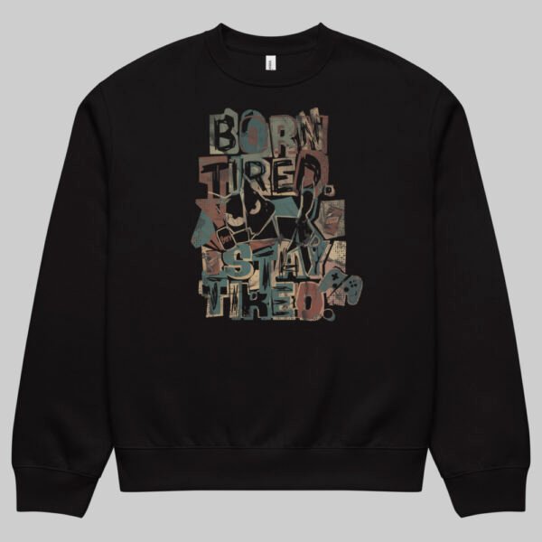 Front view of a male model wearing the Black Scowl "Born Tired Stay Tired" black crewneck sweatshirt, styled with a black cap for an edgy urban streetwear look.
