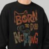 Close-up detail of the Black Scowl black sweatshirt showing the distressed texture and earthy tones of the Born to Do Nothing typography and graphic design.