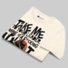 Professional flat-lay shot of a folded Black Scowl cream oversized graphic t-shirt highlighting the inner brand label and premium cotton fabric texture.