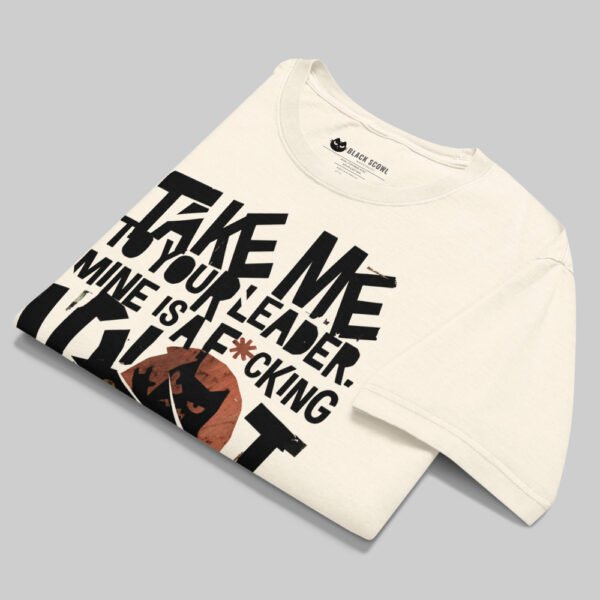 Professional flat-lay shot of a folded Black Scowl cream oversized graphic t-shirt highlighting the inner brand label and premium cotton fabric texture.