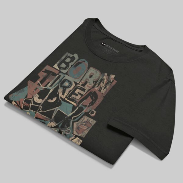 A professionally folded Black Scowl washed black graphic tee on a gray background, showcasing the durable heavyweight fabric and vibrant abstract art.
