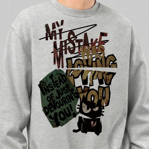Close-up detail of the Black Scowl grey crewneck sweatshirt, showcasing the urban clothing graphic with the phrase my mistake was loving you and the cynical cat.