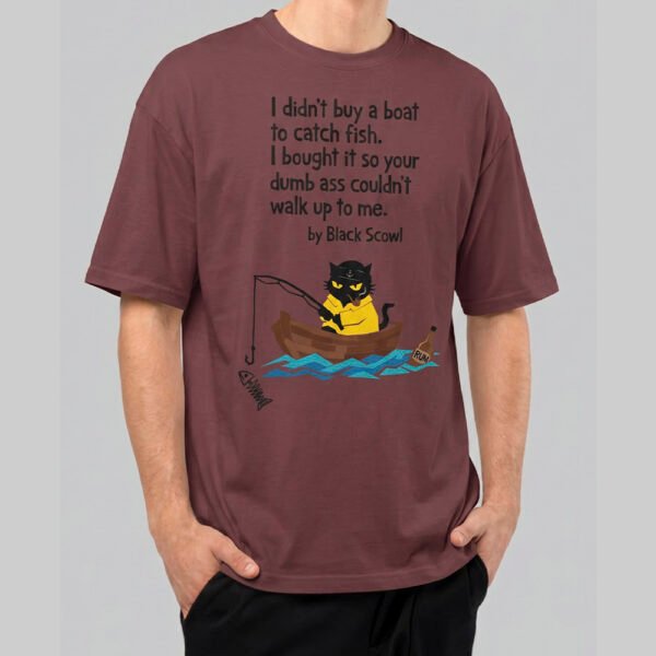 Front view of a male model wearing a Black Scowl maroon oversized t-shirt featuring a sarcastic "I didn't buy a boat to catch fish" graphic with a cat in a rowboat.