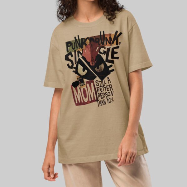 A female model wearing the Black Scowl sand-colored graphic wear tee with a relaxed avant-garde silhouette and a dark humor punk-inspired design.