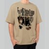 Front view of a male model wearing a Black Scowl sand-colored heavyweight t-shirt featuring a cynical "Filling Your Void" collage-style graphic with a black cat.