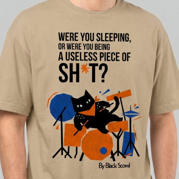 Close-up detail of the Black Scowl sand heavyweight tee showing the high-quality print of the abstract cat drummer and bold cynical typography.