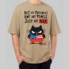 Front view of a male model wearing a Black Scowl sand-colored oversized t-shirt featuring a cynical "Just My Nap" political satire graphic with a black cat.