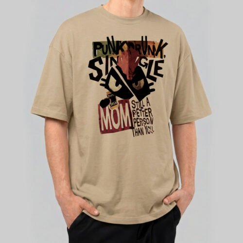 Front view of a male model wearing a Black Scowl sand-colored oversized t-shirt featuring a cynical "Punk Drunk Single Mom" graphic with a cat illustration.