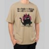Front view of a male model wearing a Black Scowl sand oversized t-shirt with a sarcastic cat on a skateboard graphic and "Too broke for therapy" text.
