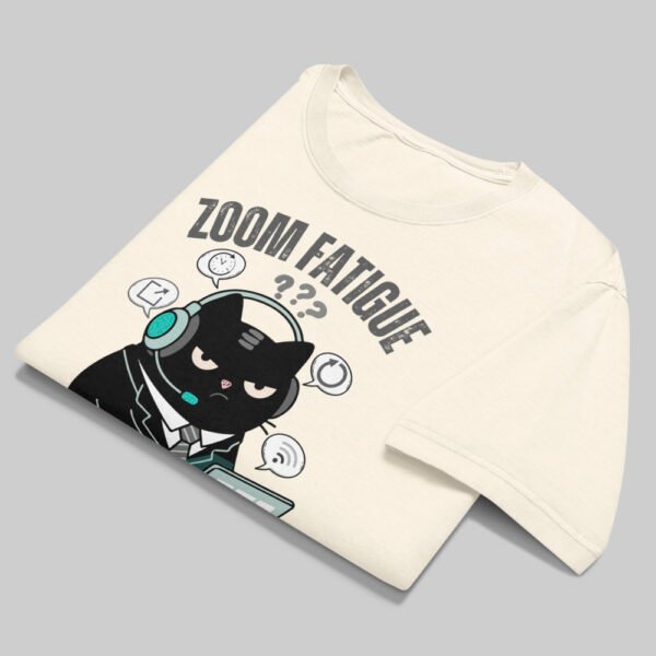 A folded Black Scowl graphic tee on a grey surface displaying a minimalist streetwear aesthetic with a sarcastic office cat design and high-quality print detail.