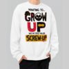 A male model wearing a Black Scowl white sweatshirt featuring a graphic cat design and the sarcastic text Wanting to Grow Up Was My First Major Screw Up in an urban streetwear style.