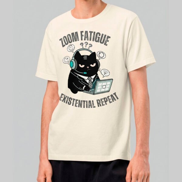 A man wearing a Black Scowl cream-colored graphic t-shirt featuring a grumpy office cat with the text Zoom Fatigue Existential Repeat in a vintage streetwear style.