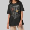 A female model wearing the Black Scowl black heavyweight graphic tee with a modern oversized fit and cynical avant-garde urban style.